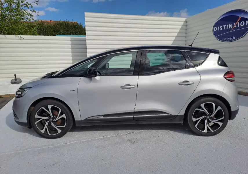 Profil droit d'un Renault Scénic IV gris platine avec toit noir, jantes noires et détails modernes visibles.