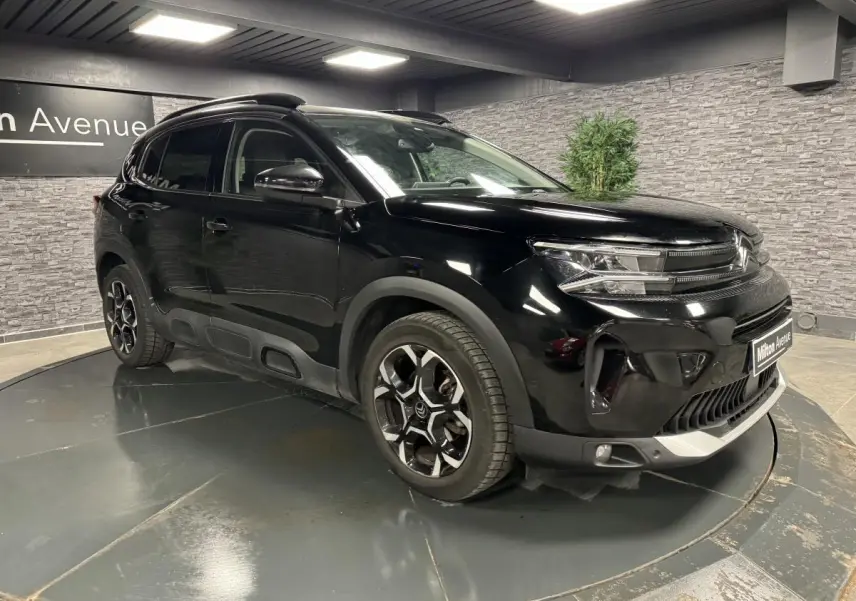 Vue 3/4 avant d'un Citroën C5 Aircross noir nacré avec jantes bi-ton et barres de toit noir brillant.