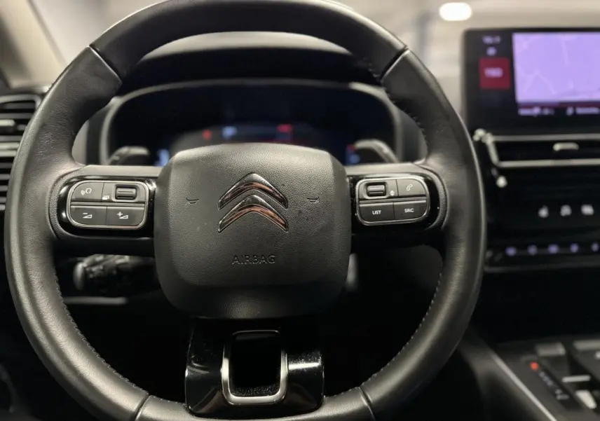 Volant en cuir noir avec commandes intégrées et logo Citroën, tableau de bord numérique et écran tactile à droite