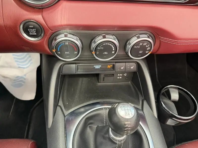 Vue rapprochée de la console centrale du Mazda MX-5 noir 2020, avec levier de vitesse manuel et commandes de climatisation rouges.