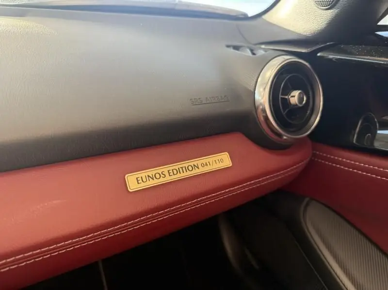 Détail intérieur côté passager de la Mazda MX-5 noire 2020 avec plaque EUNOS EDITION sur tableau de bord rouge.