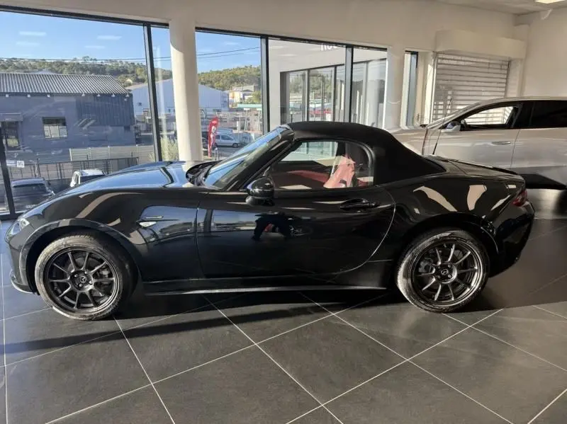 Mazda MX-5 1.5 SKYACTIV-G noir vue de profil côté gauche, capote fermée et jantes noires en showroom.