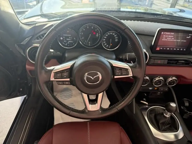 Vue intérieure centrée sur le volant Mazda d'une MX-5 noire 2020, avec tableau de bord et levier de vitesse manuel visibles.