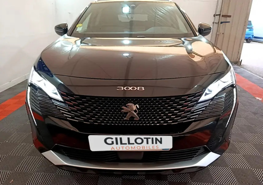 Vue frontale du Peugeot 3008 noir avec calandre distinctive et phares LED allumés en intérieur showroom.