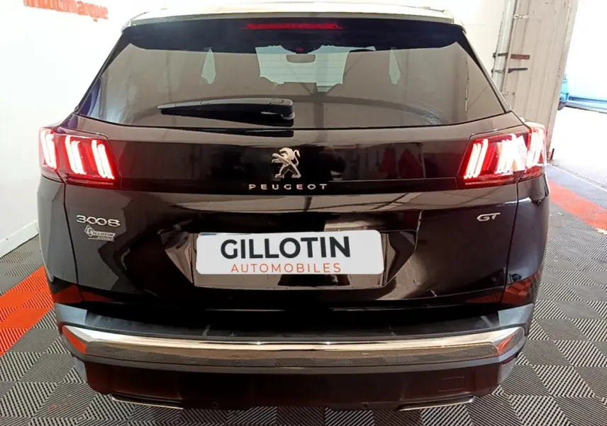 Vue arrière d'un Peugeot 3008 GT noir avec feux LED allumés et logo Peugeot visible sur le hayon.