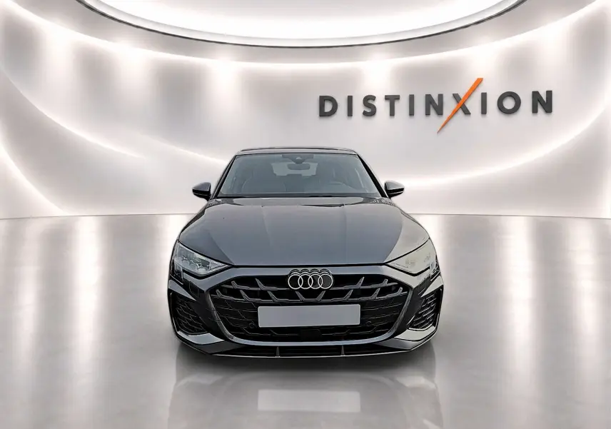 Audi A3 Sportback gris Daytona vue de face dans un showroom avec logo Distinxion en arrière-plan.