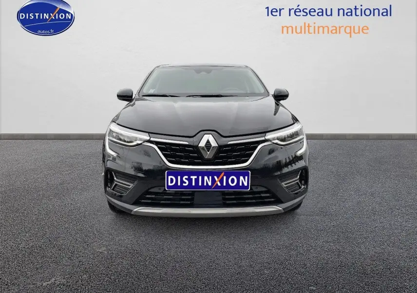 Vue frontale d'un Renault Arkana noir métal 2023 avec calandre chromée et phares LED allumés.