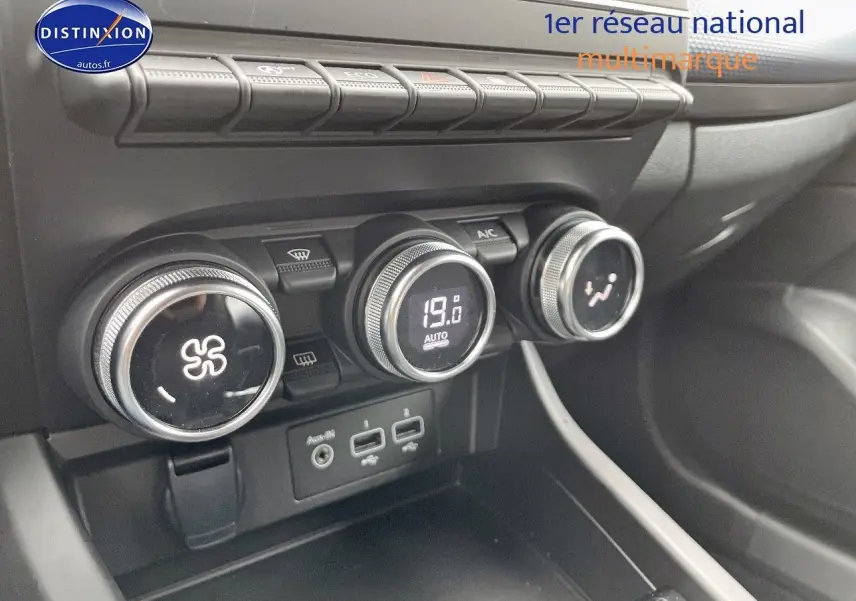 Gros plan sur la console centrale de la Renault Arkana noire, montrant les commandes de climatisation et ports USB.