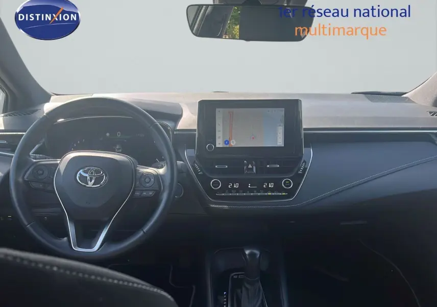 Vue intérieure frontale du tableau de bord et volant noir de la Toyota Corolla 2023 avec écran tactile et commandes intégrées.