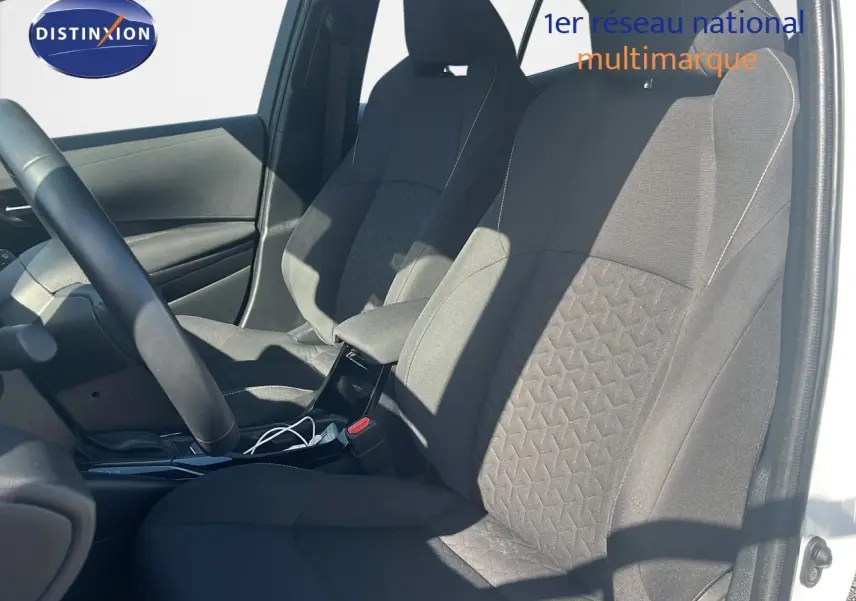 Intérieur de la Toyota Corolla 2023 blanc pur, vue côté gauche sur les sièges avant en tissu noir avec motifs géométriques.