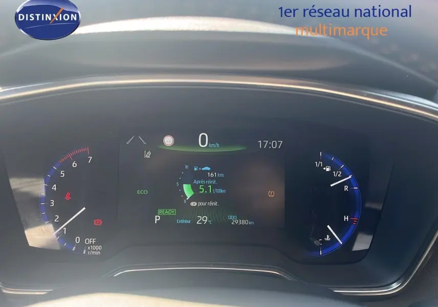 Tableau de bord numérique de la Toyota Corolla blanche 2023, affichant vitesse, consommation et température extérieure.