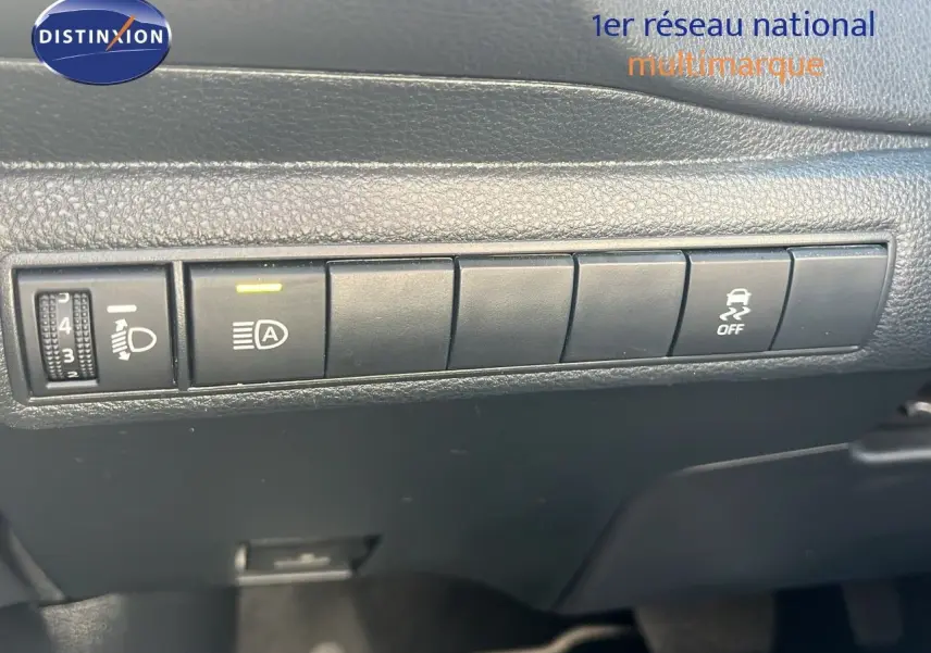 Gros plan sur les commandes de réglage des phares et de l'ESP dans l'habitacle d'une Toyota Corolla blanche 2023.