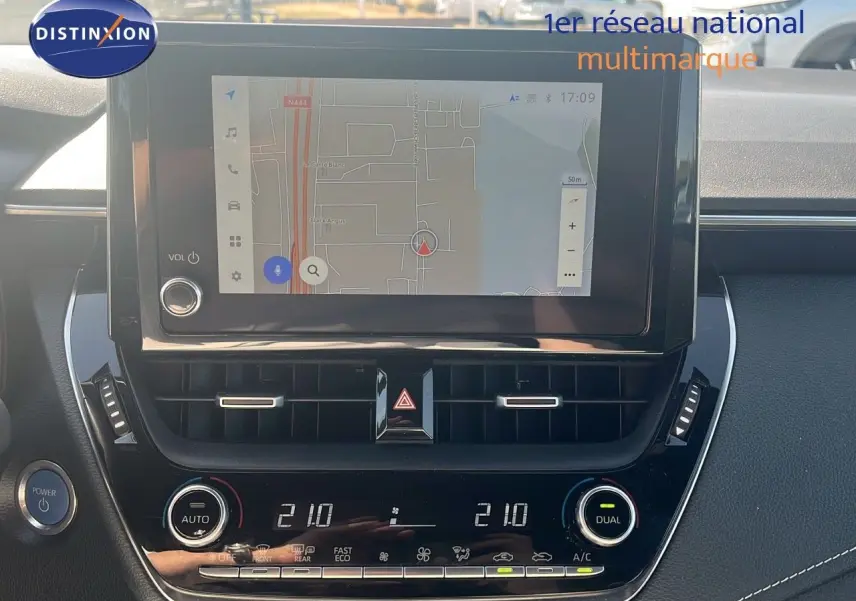 Vue rapprochée de l'écran tactile et de la console centrale noire de la Toyota Corolla blanche hybride 2023.