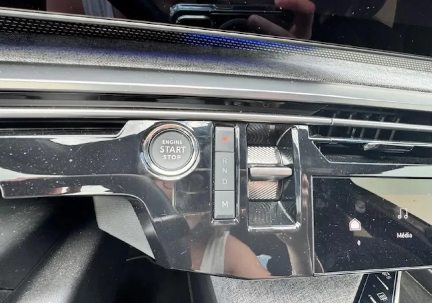 Gros plan sur la console centrale noire brillante du Peugeot 3008 2024 avec bouton start/stop et sélecteur de vitesses.