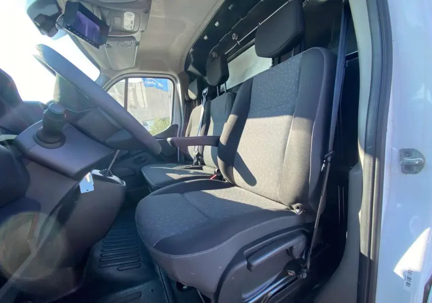 Vue intérieure côté conducteur du fourgon blanc Opel Movano 2021, montrant les sièges avant et le volant.