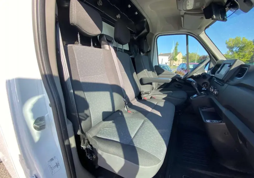 Vue intérieure côté conducteur de l'Opel Movano Fourgon blanc, montrant les sièges avant et le tableau de bord.
