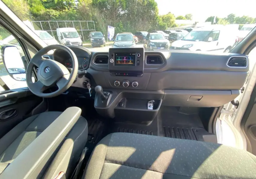 Vue intérieure avant de l'Opel Movano Fourgon blanc 2021, tableau de bord avec écran tactile et volant à gauche.