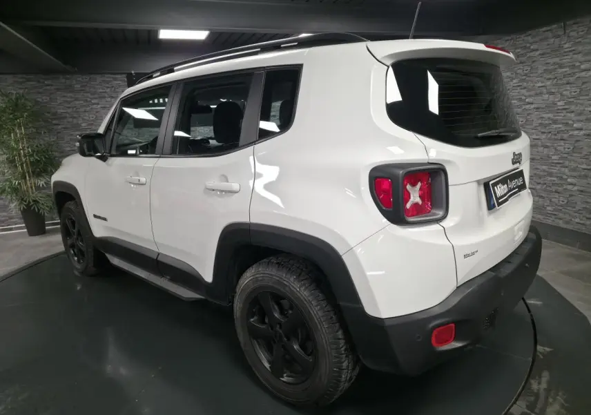 Jeep Renegade blanc vu en 3/4 arrière droit avec jantes noires 5 branches et barres de toit gris clair.