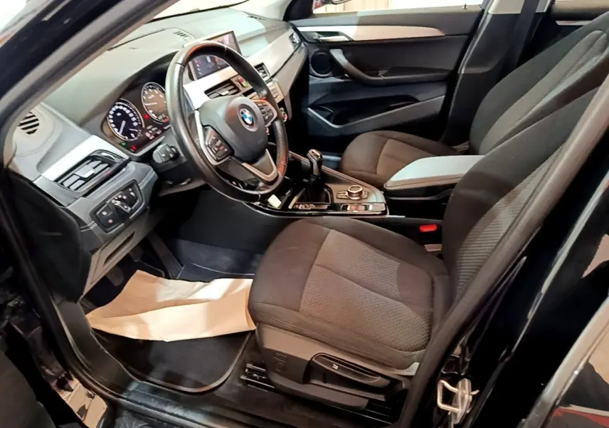 Intérieur noir de la BMW X2 sDrive18i 2023 vu côté conducteur, avec volant cuir et boîte manuelle.