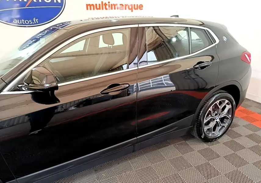 Vue latérale droite d'un BMW X2 sDrive18i Lounge noir brillant, mettant en valeur les jantes et la ligne de caisse élégante.