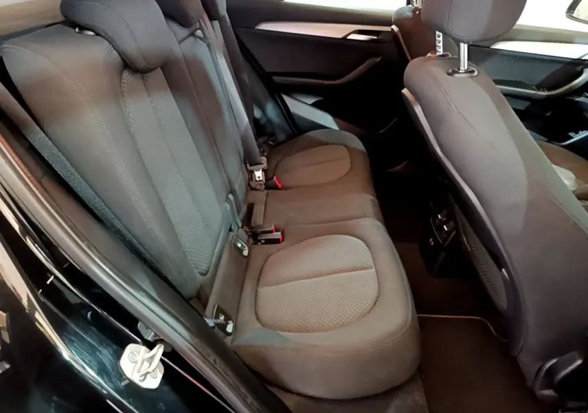 Vue intérieure côté gauche des sièges arrière noirs en tissu du BMW X2 sDrive18i Lounge 2023 avec port USB et aérateurs.