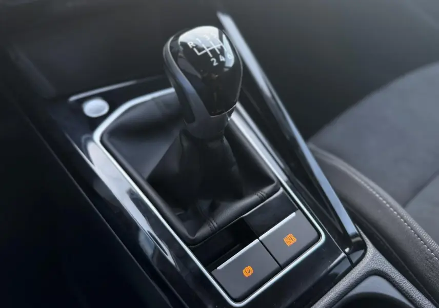 Gros plan sur le levier de vitesses manuel noir et la console centrale brillante de la Volkswagen Golf VIII 2024.