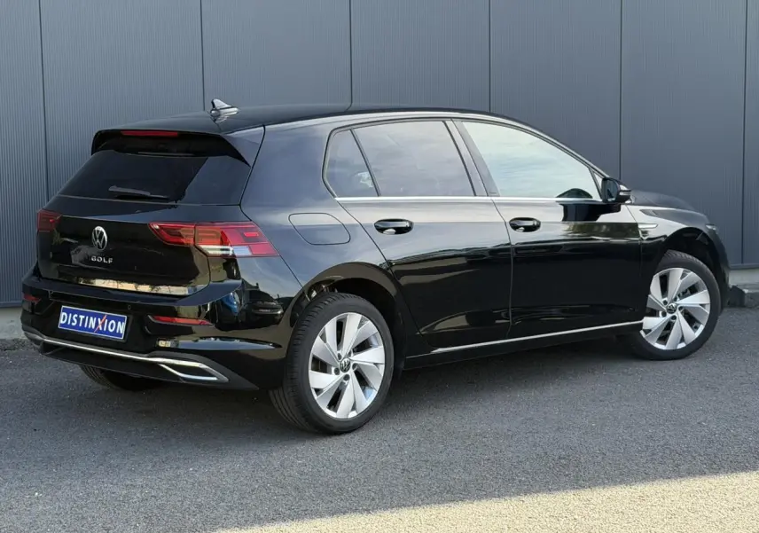 Vue 3/4 arrière droite d'une Volkswagen Golf VIII noire avec jantes alliage 17 pouces et baguettes chromées.