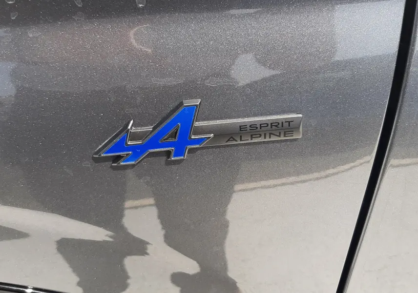 Gros plan sur l'écusson bleu "A" et la mention Esprit Alpine sur la carrosserie gris schiste métallisé du Renault Espace.