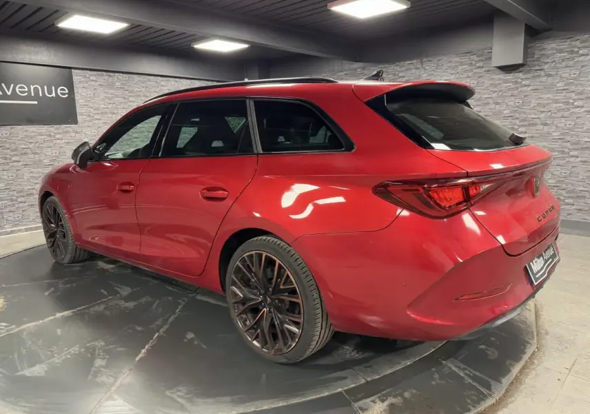Vue 3/4 arrière droite d'une CUPRA Leon Sportstourer rouge Désir avec jantes alliage 19 pouces et toit noir.
