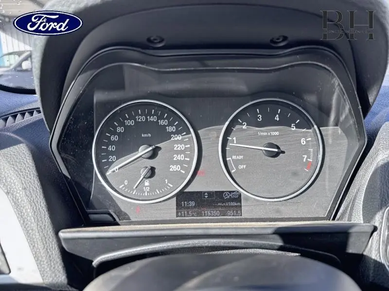 Tableau de bord BMW Série 1 114i 2013 vu de face, avec compte-tours et compteur de vitesse noirs.