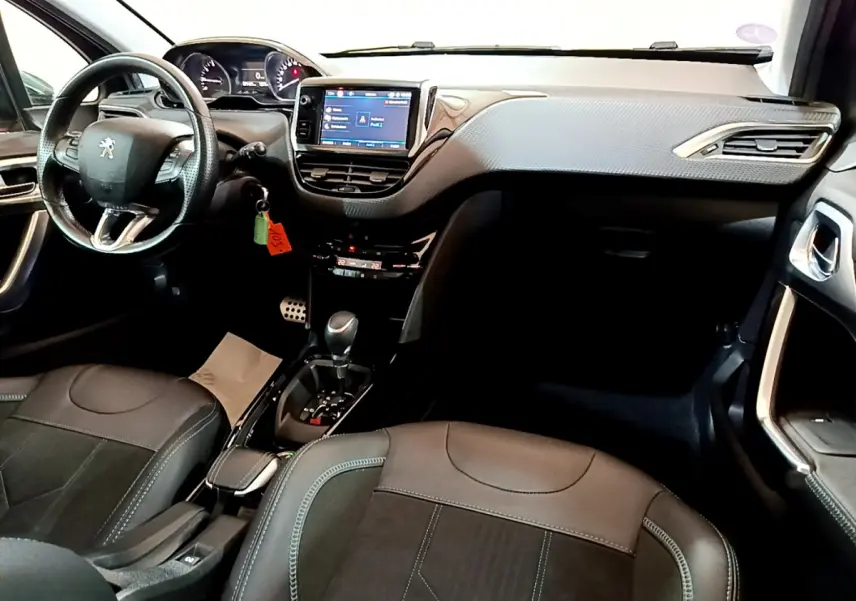 Intérieur de la Peugeot 2008 gris foncé, vue de face montrant le tableau de bord avec écran tactile et volant cuir multifonctions.