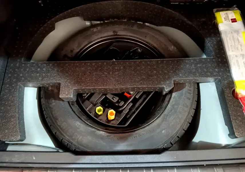 Vue plongeante sur la roue de secours et les outils dans le coffre du Peugeot 2008 gris foncé de 2019.