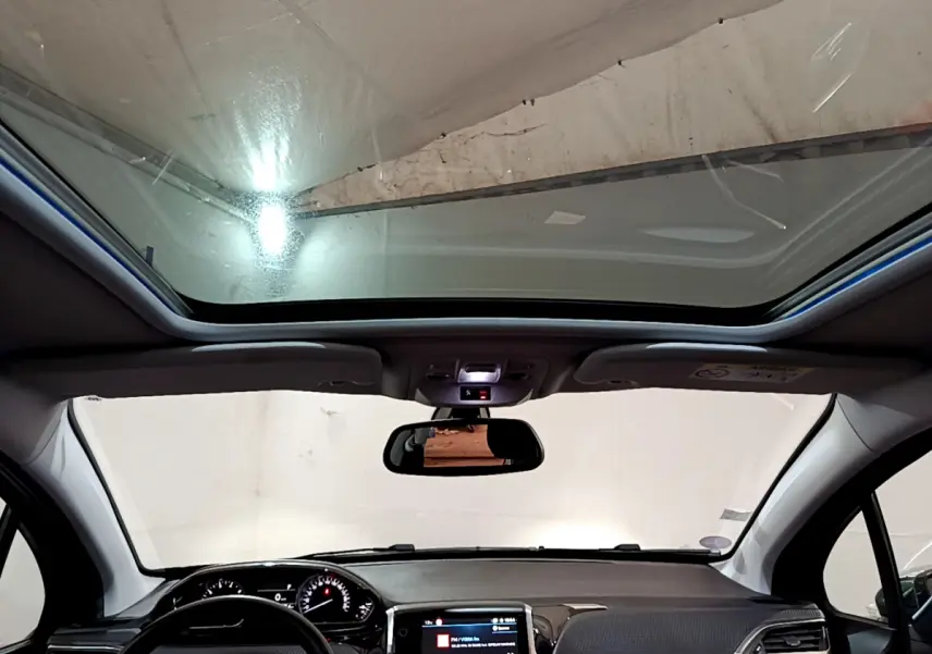 Vue intérieure avant du Peugeot 2008 gris foncé 2019, mettant en valeur le toit panoramique et l'écran tactile central.