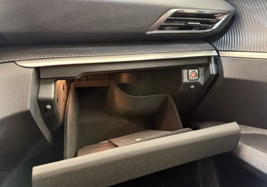 Vue intérieure du coffre à gants ouvert du Peugeot 3008 bleu, montrant la texture du tableau de bord et une lumière intérieure.