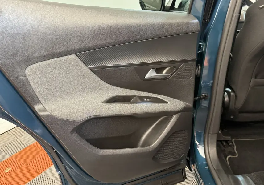 Vue intérieure de la porte arrière gauche bleu métallisé du Peugeot 3008 avec garniture tissu et plastique noir.