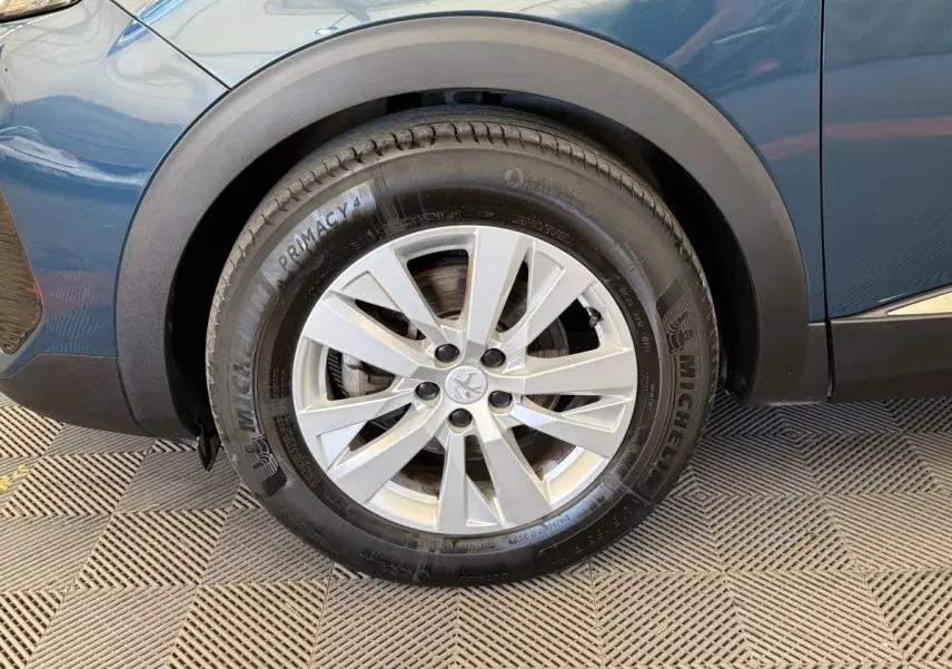 Gros plan sur la roue avant gauche d’un Peugeot 3008 bleu, avec jante alliage argentée et pneu Michelin.