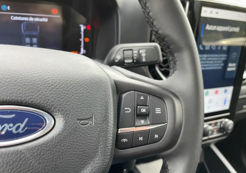 Gros plan sur le volant cuir multifonctions du Ford Ranger gris carbone avec écran tactile et commandes au volant visibles.