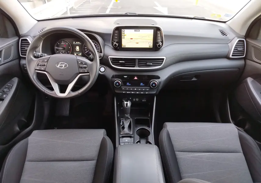 Vue intérieure avant du Hyundai Tucson 2019, tableau de bord gris avec écran tactile et volant multifonction.