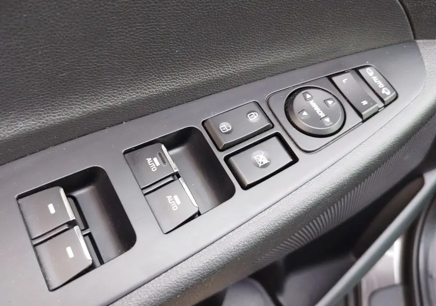 Gros plan sur les commandes de lève-vitres et réglages des rétroviseurs côté conducteur d’un Hyundai Tucson gris Micron 2019.
