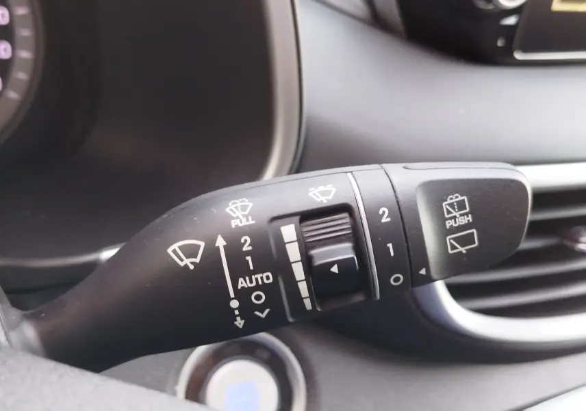 Gros plan sur la commande des essuie-glaces du Hyundai Tucson 2019, avec détails des réglages en blanc sur fond noir.