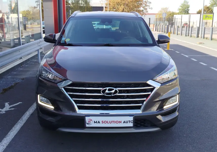 Vue avant d'un Hyundai Tucson gris Micron 2019 avec calandre chromée et feux LED allumés.