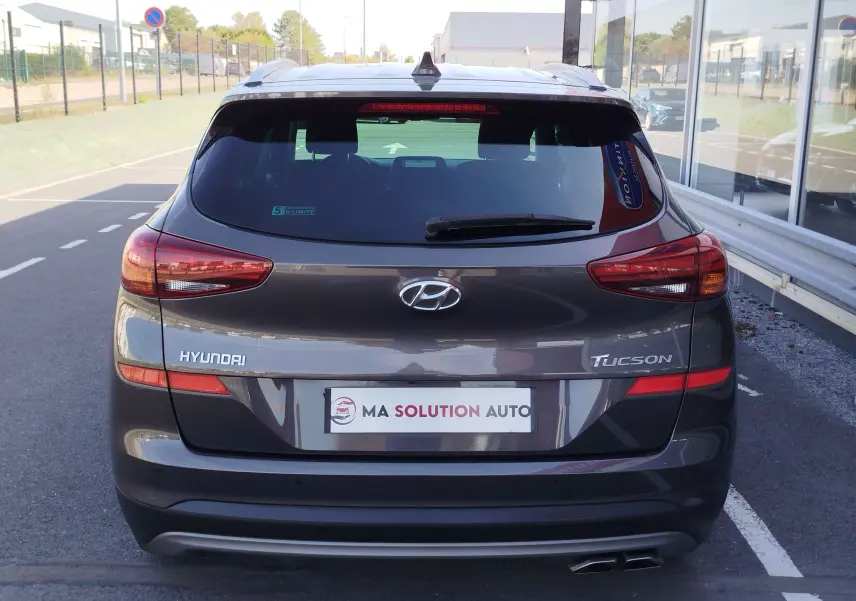 Vue arrière d'un Hyundai Tucson gris micron 2019, avec feux arrière allongés et double sortie d'échappement visible.