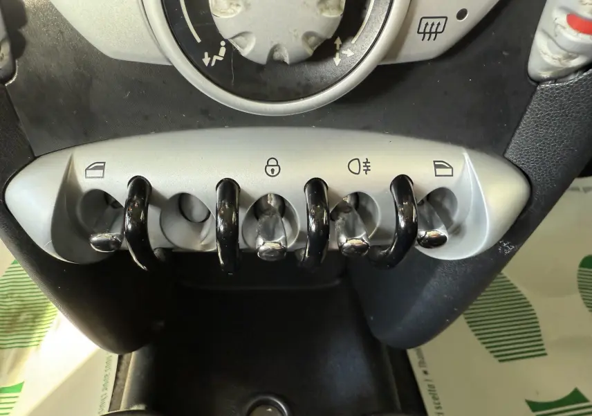 Gros plan sur les commandes à bascule argentées du tableau de bord d'une MINI Cooper bleu 2007.