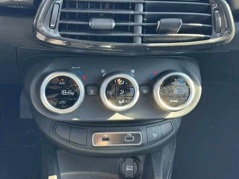 Gros plan sur les commandes de climatisation automatique bi-zone de la FIAT 500X rouge Passione pastel, avec affichage digital.