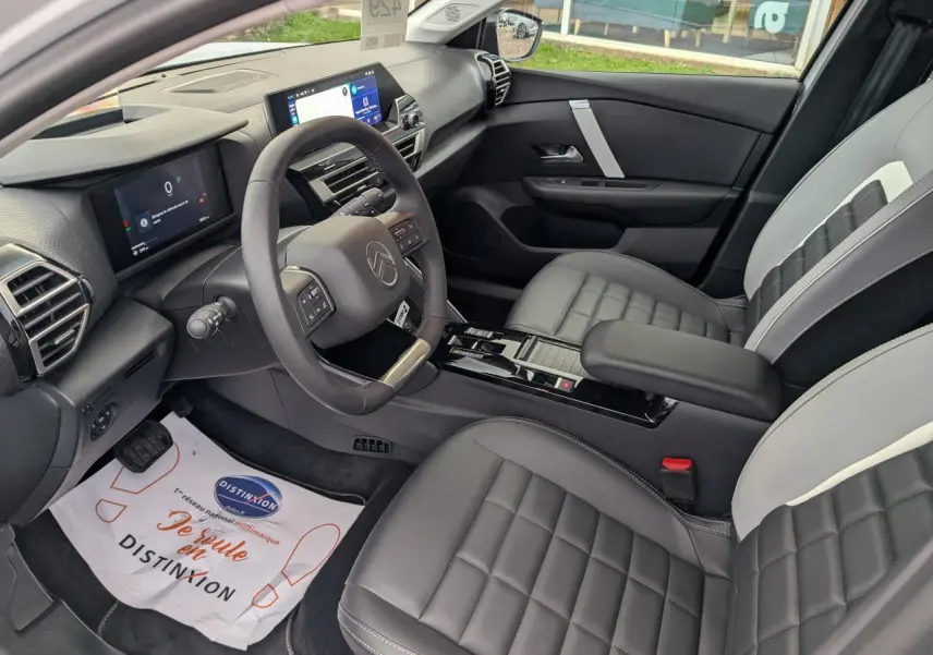 Intérieur avant droit de la Citroën C4 2025 blanc, avec sièges bicolores et tableau de bord numérique moderne.