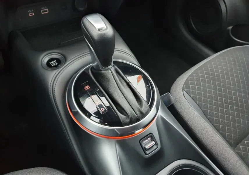 Gros plan sur la commande de boîte automatique noire et bouton Start/Stop du Nissan Juke 2025, intérieur tissu gris.