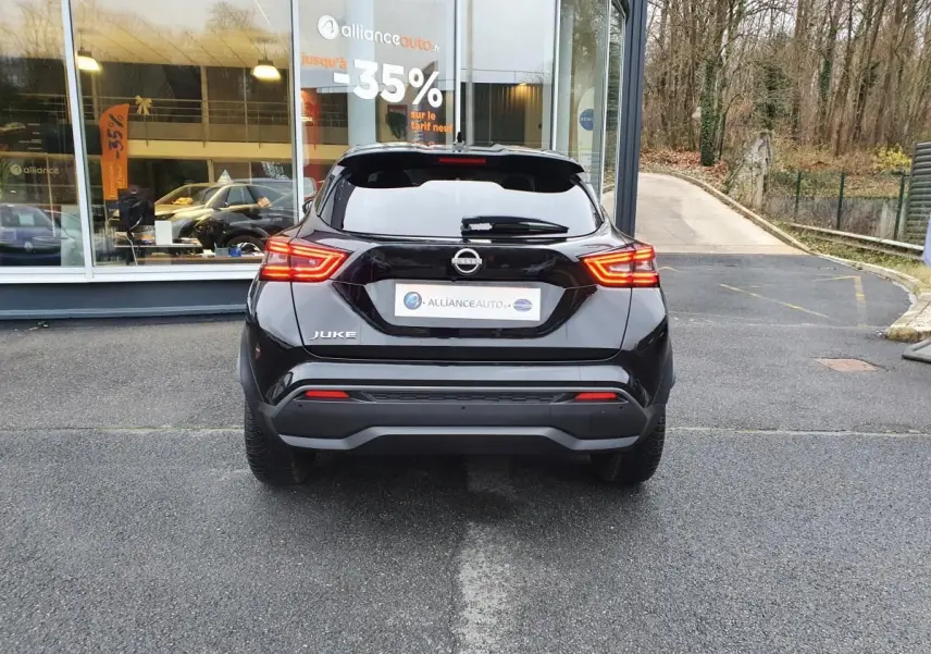 Vue arrière d'un Nissan Juke noir 2025 avec feux LED allumés, garé devant une vitrine de concession.