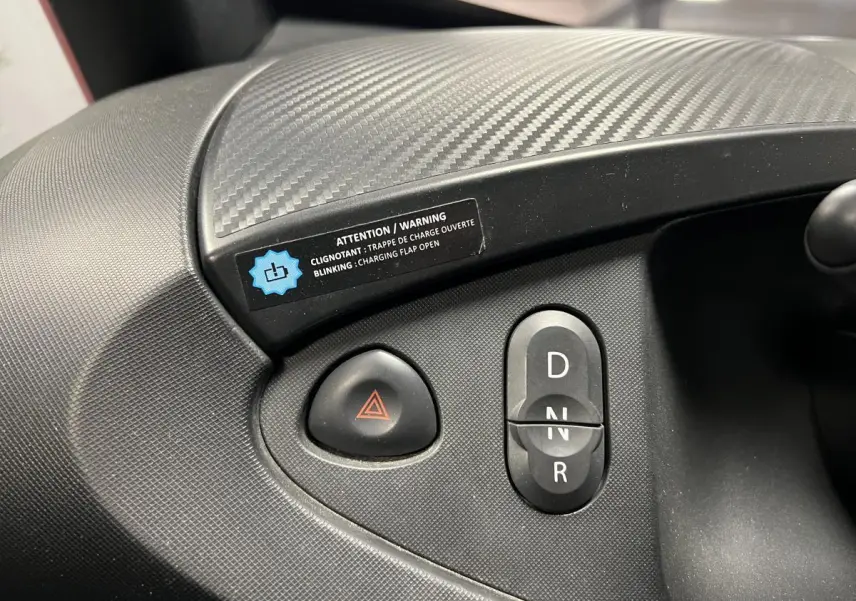 Gros plan sur la console centrale noire de la Renault Twizy Intens 2019 montrant les boutons de feux de détresse et de sélection de vitesse.