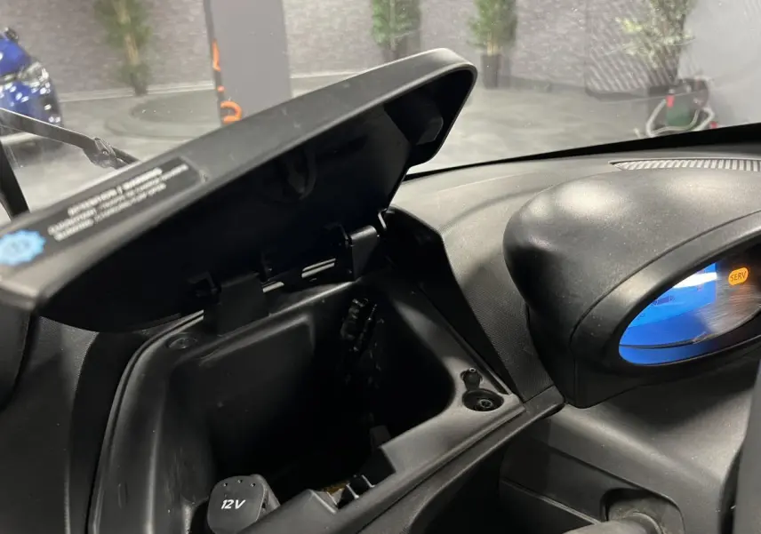 Boîte à gants ouverte côté droit du tableau de bord noir d'une Renault Twizy orange 2019 électrique.