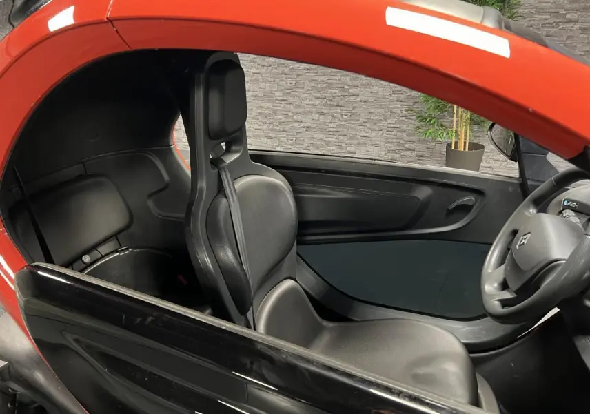 Intérieur côté gauche de la Renault Twizy orange 2019, avec siège noir et volant visible au premier plan.